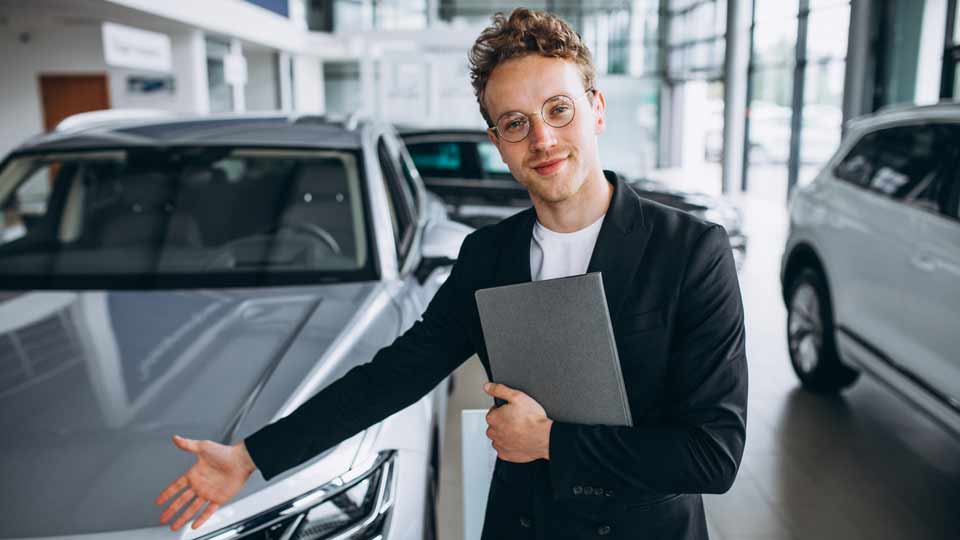 Ein Verkäufer zeigt auf ein Auto und erklärt dem Kunden die Konditionen beim Auto verkaufen Sinsheim